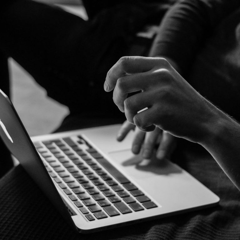 Für wen geeignet Person sitzt im Schneidersitz und arbeitet an einem Laptop auf einer geflochtenen Matte.