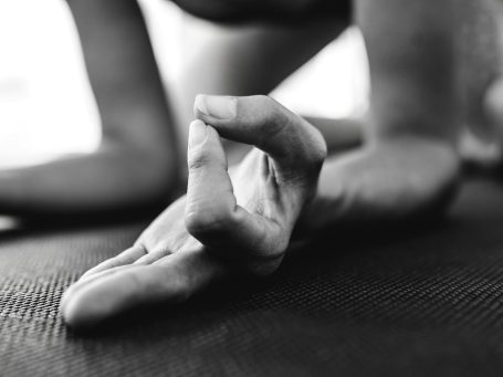 Eine Hand in Meditationsposition auf einer Yogamatte, nahe dem Boden.