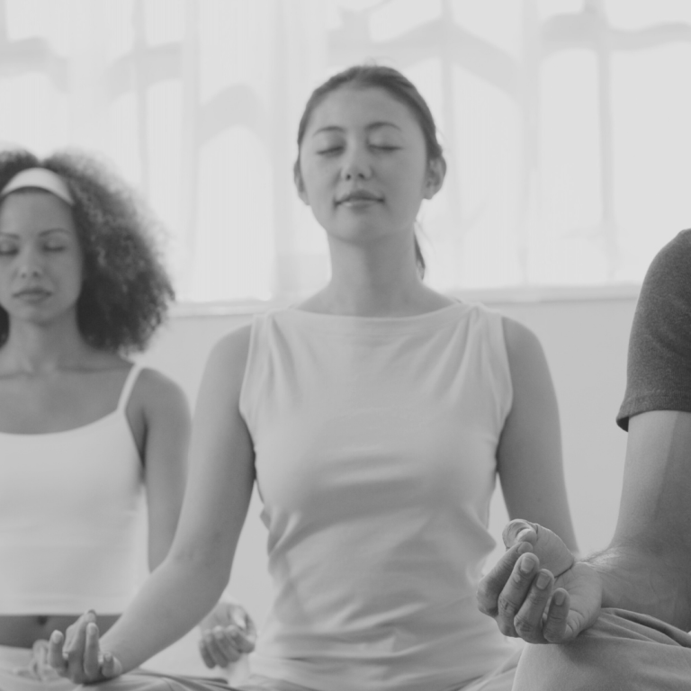 Businessyoga Drei Menschen meditieren in einer hellen Umgebung mit geschlossenen Augen.